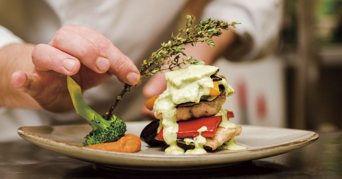 chef putting aromatic herbs on a plate